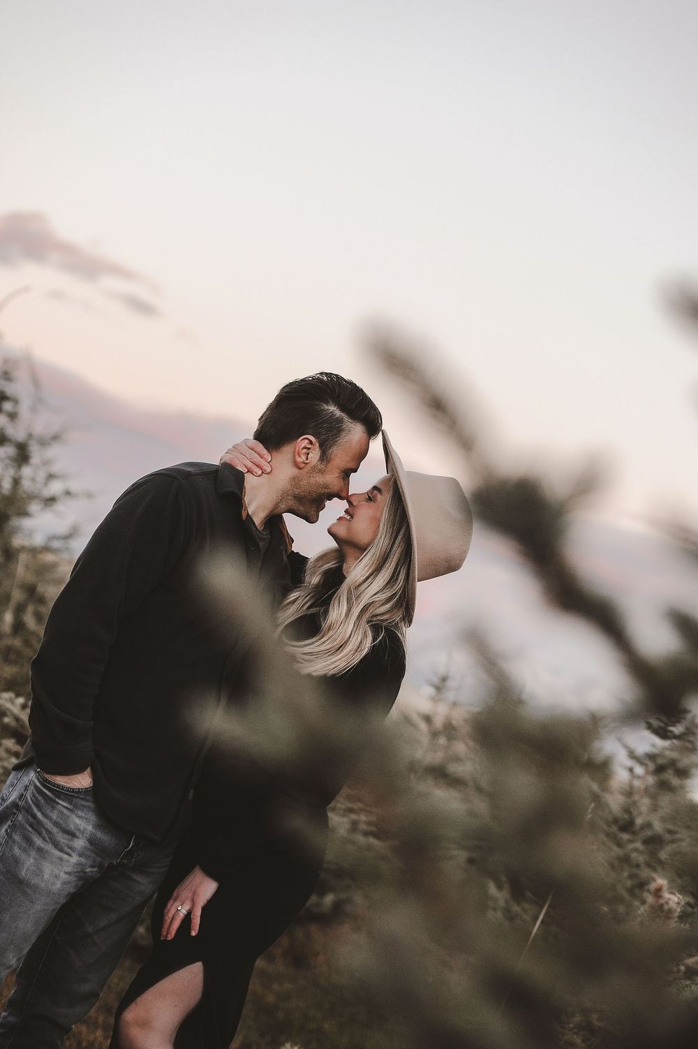 Romantic couple embracing in natural outdoor setting during sunset.