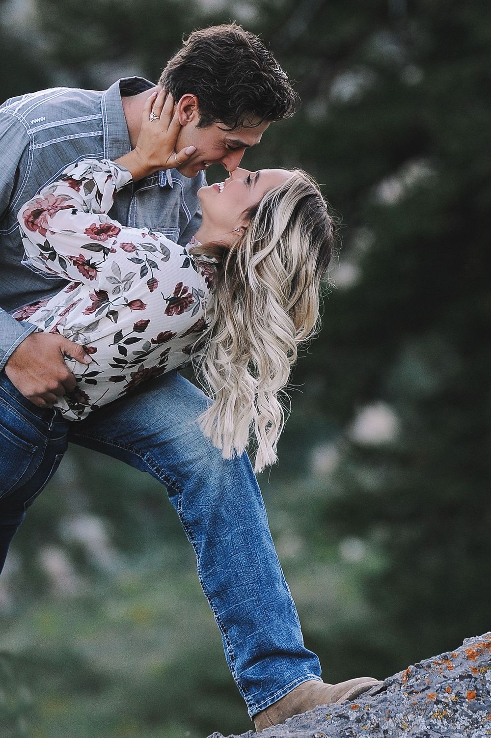 Romantic couple sharing an intimate moment on rocky terrain at dusk.