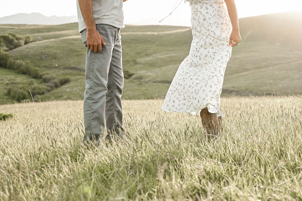 Lower body shot of couple walking through tall grass in golden sunlight.