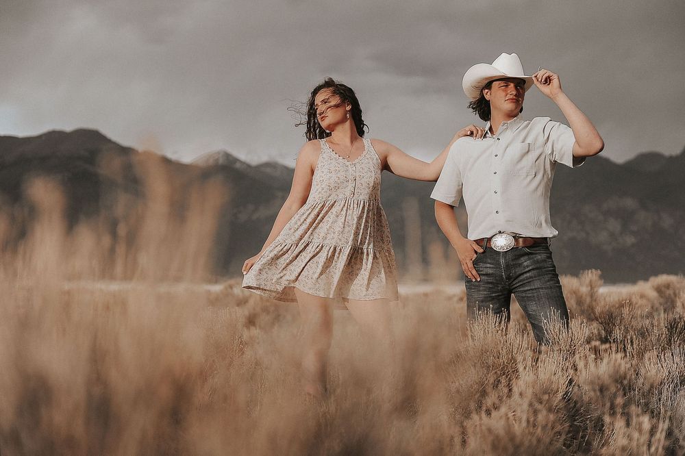 A couple dances together in a desert landscape with mountains in the background.