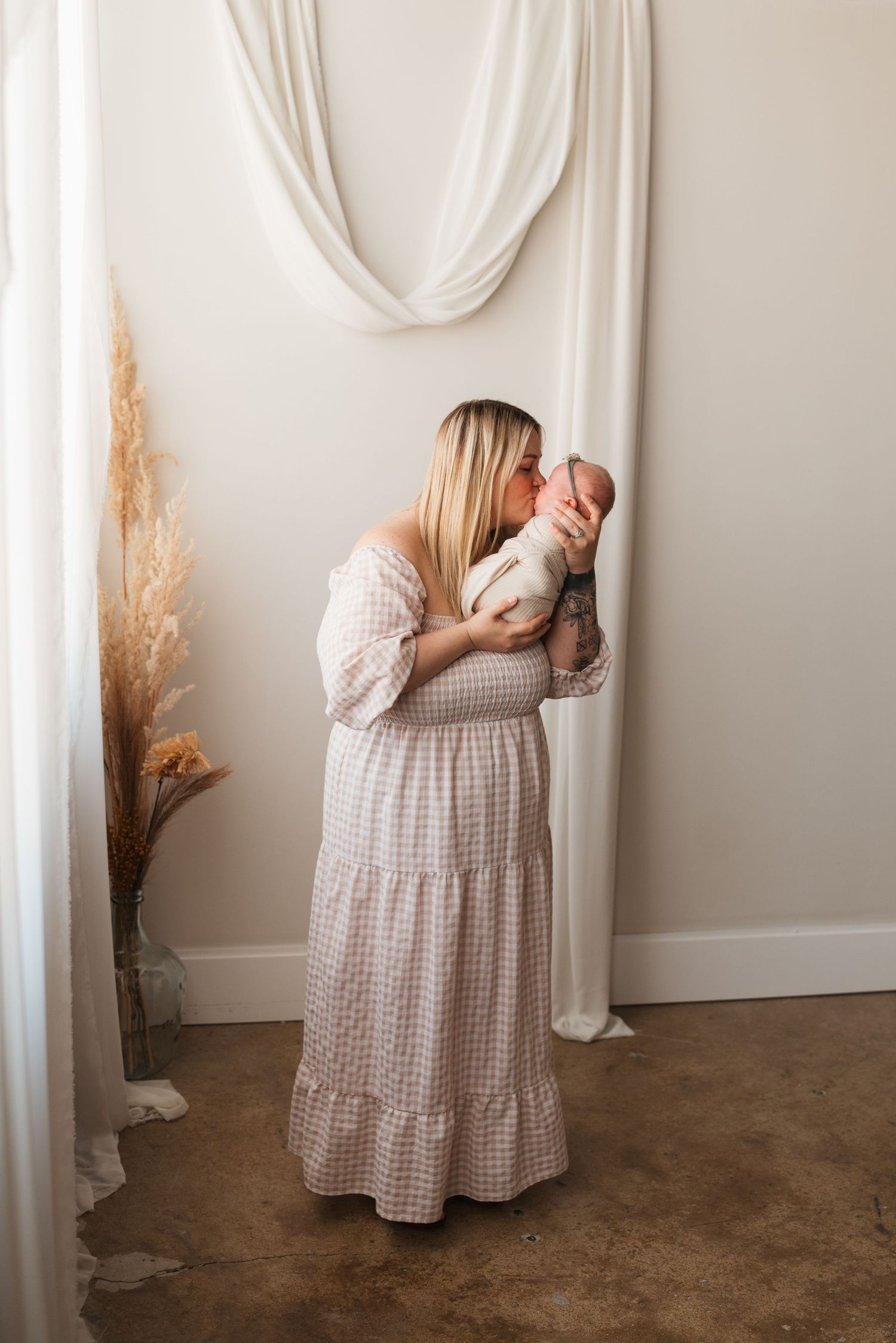 A tender moment in a white room with parent holding swaddled newborn.