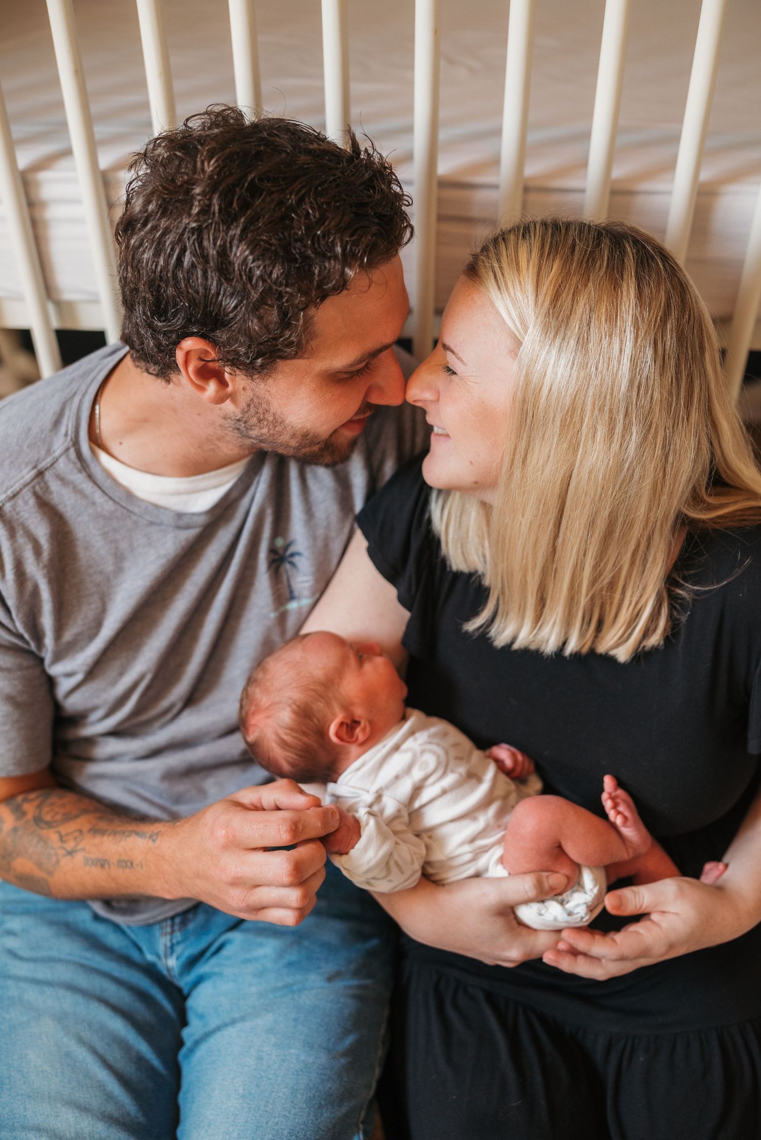 Couple sitting together on couch sharing intimate moment with their newborn baby.