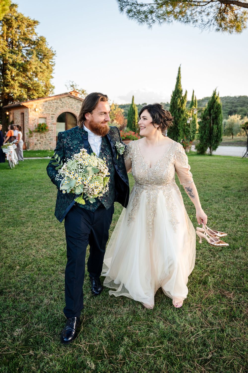 Newlyweds dance and twirl together on a grassy lawn during golden hour.