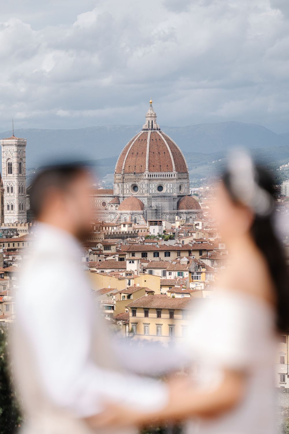 Dreamy wedding portrait with Florence's majestic Duomo cathedral in soft focus.