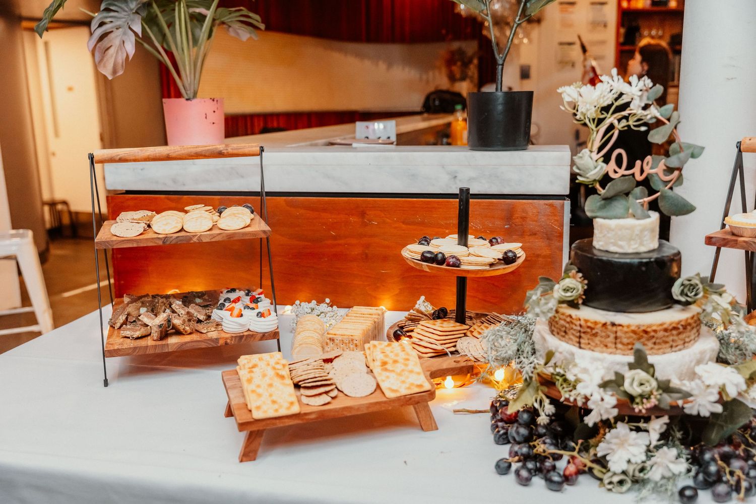 Wedding dessert table features cupcakes, cookies, and elegant white floral decorations on tiered stands.