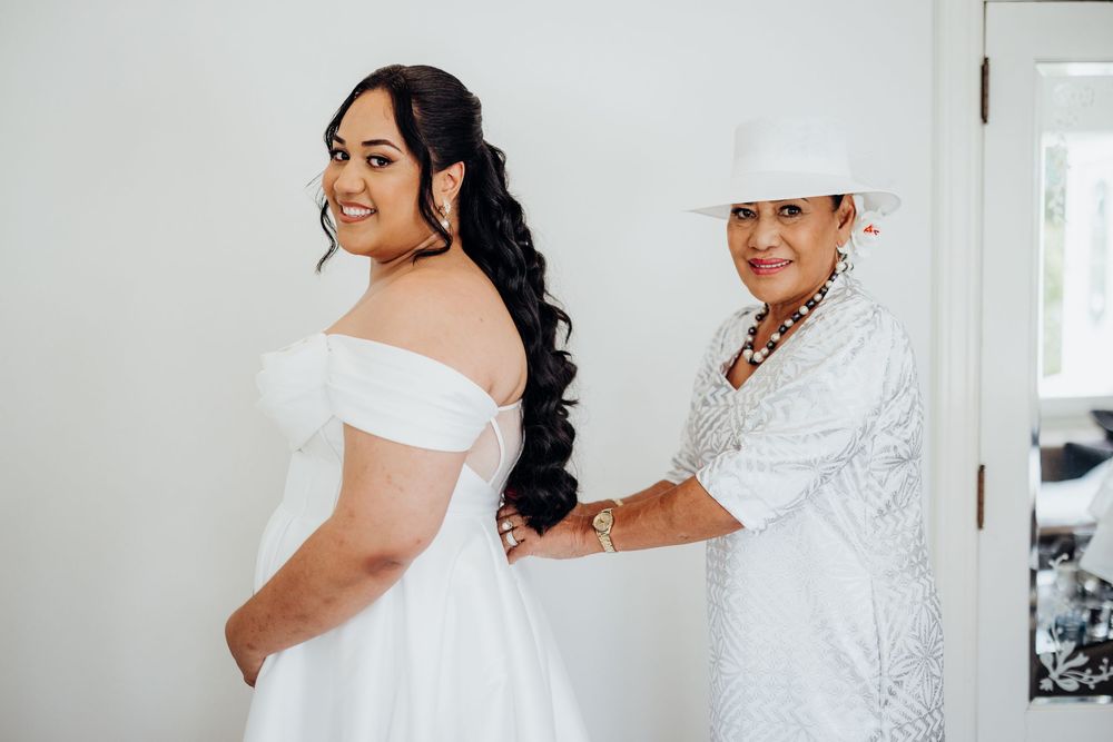 Elegant wedding dress preparations and final touches in a bright white room.
