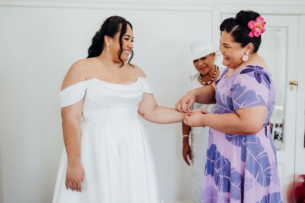 Wedding party getting ready in light-filled room wearing purple and white attire.