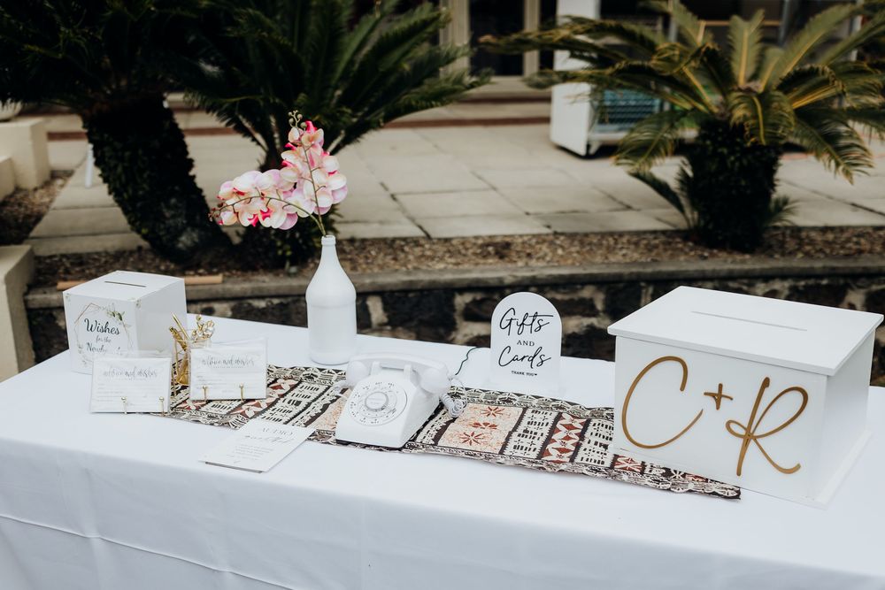Wedding signage and decorations displayed along a stone wall path with tropical palm trees.