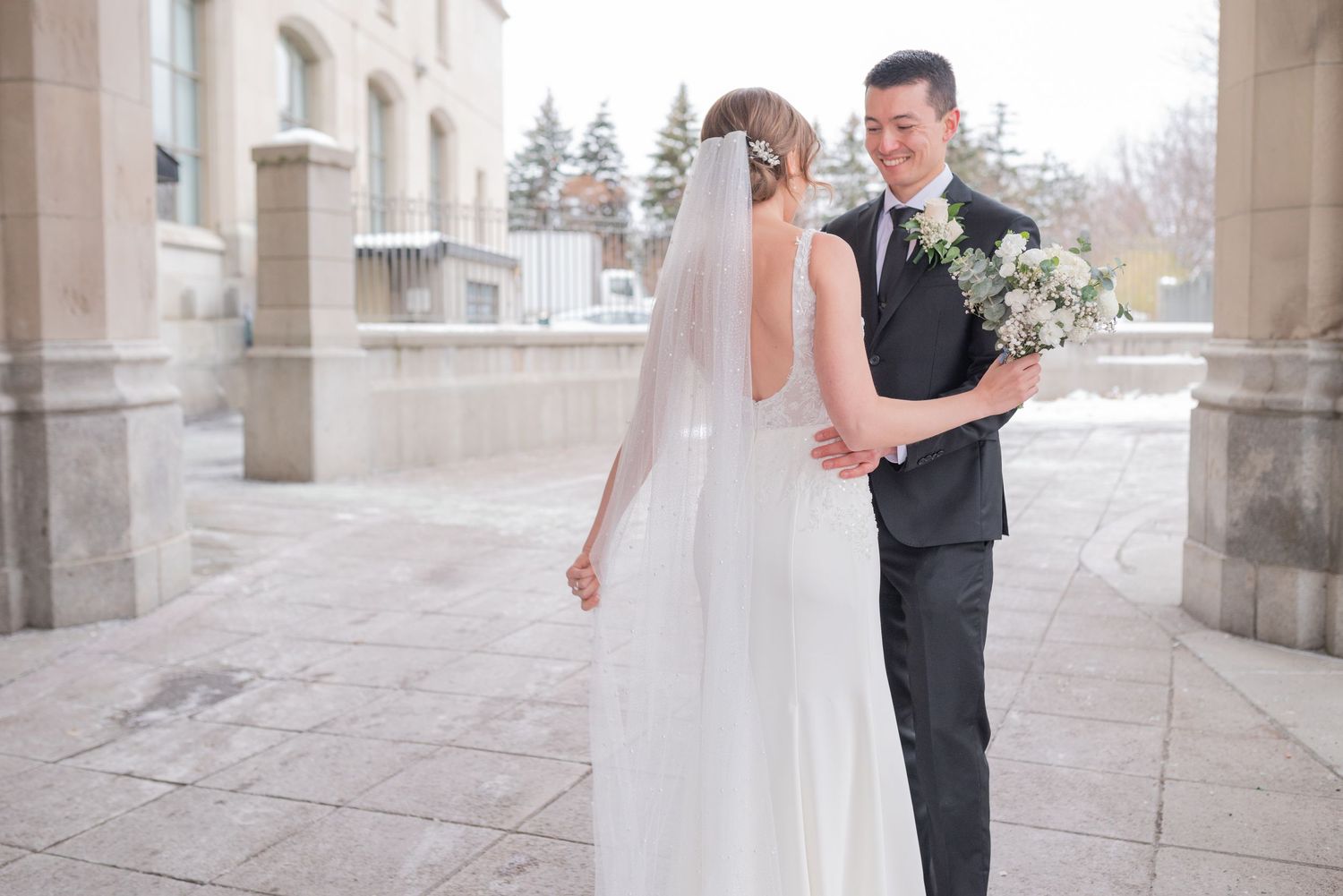 Bride and groom share joyful first look in front of Château Laurier in winter