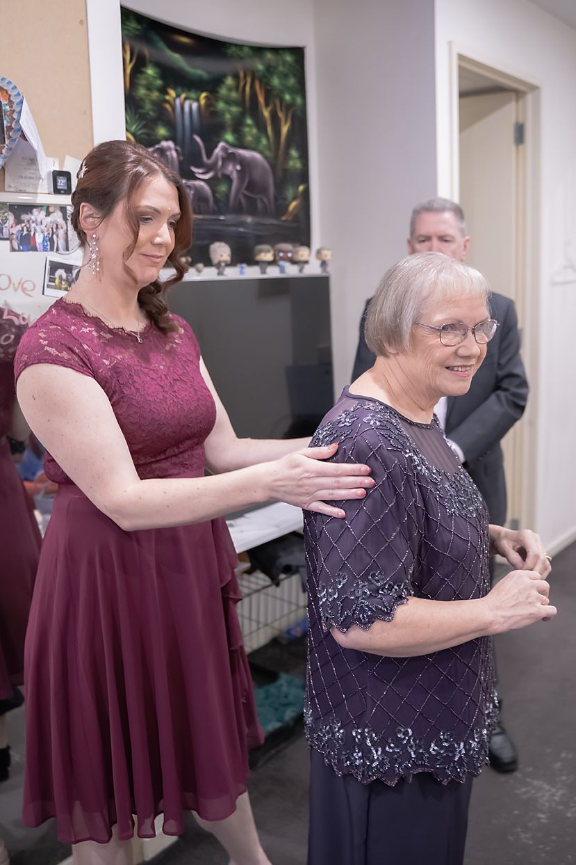 Burgundy lace dress and navy embellished top worn by two people in a casual setting against a decorated wall.