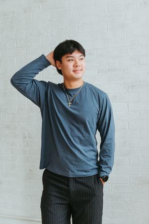 A figure in a blue sweater and pinstriped pants poses playfully against a white brick wall in a photo series.