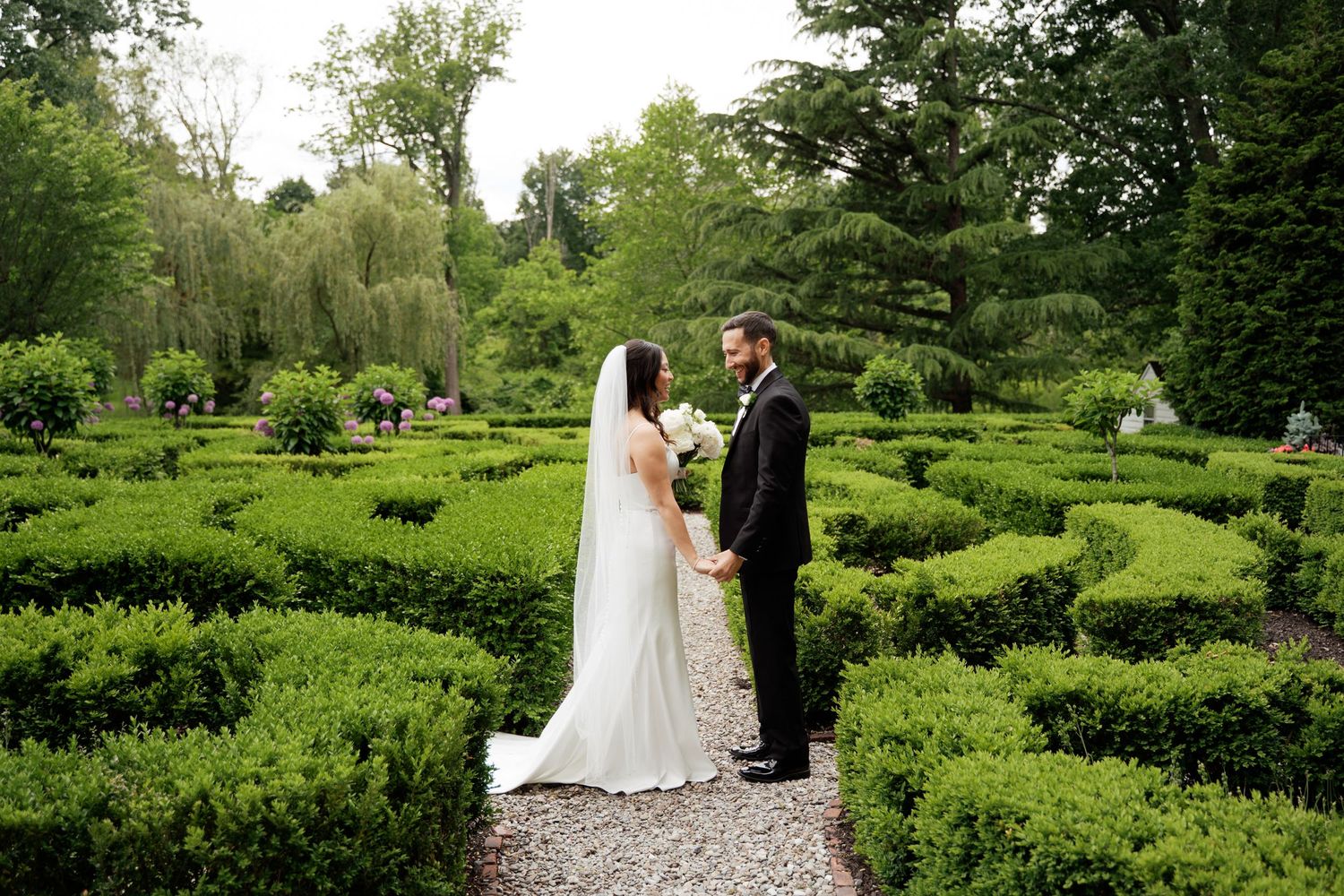 Two people share an emotional embrace under twinkling string lights at an outdoor evening event.