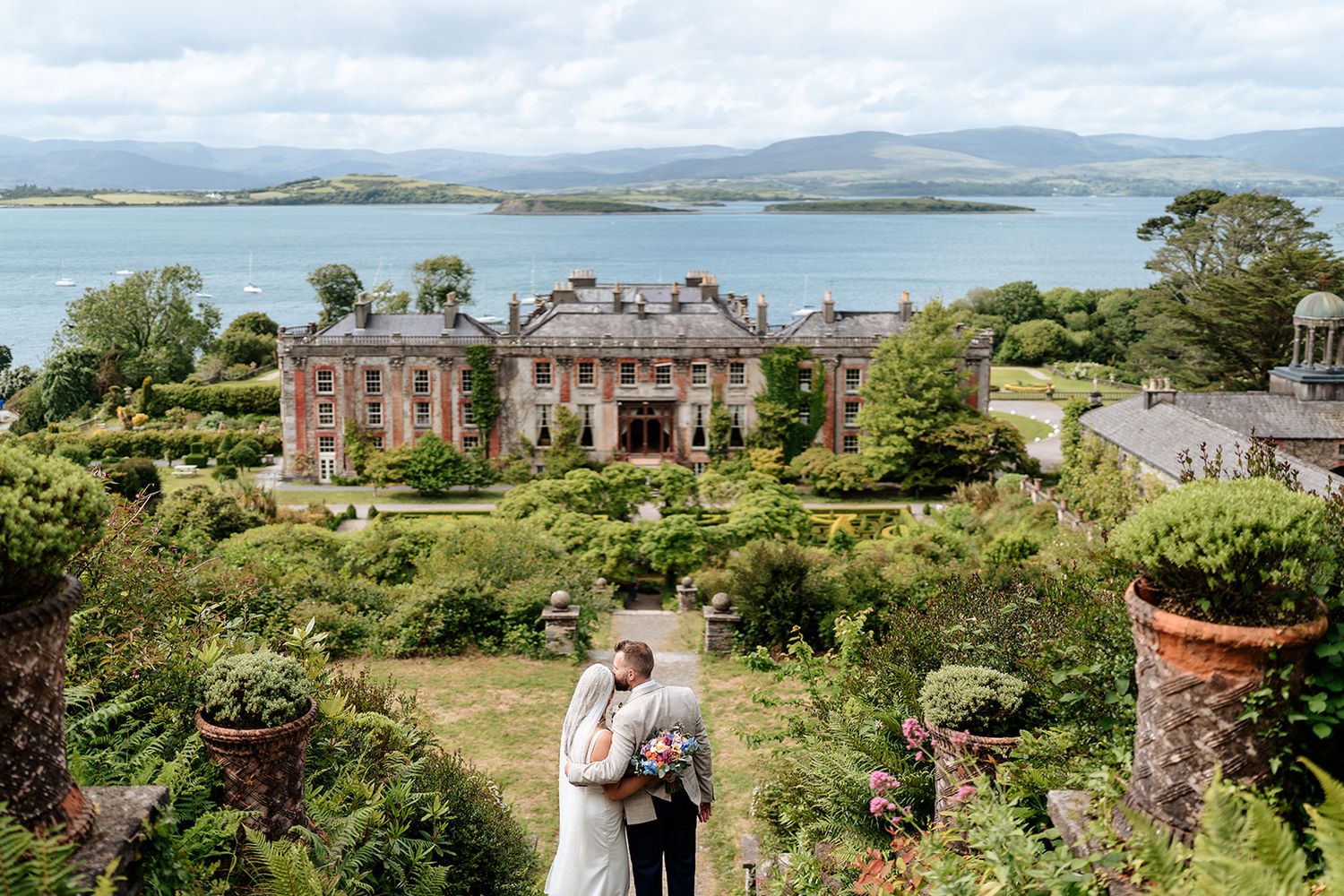 Scenic coastal wedding venue in Ireland with rolling hills, historic buildings and lush gardens overlooking the sea.
