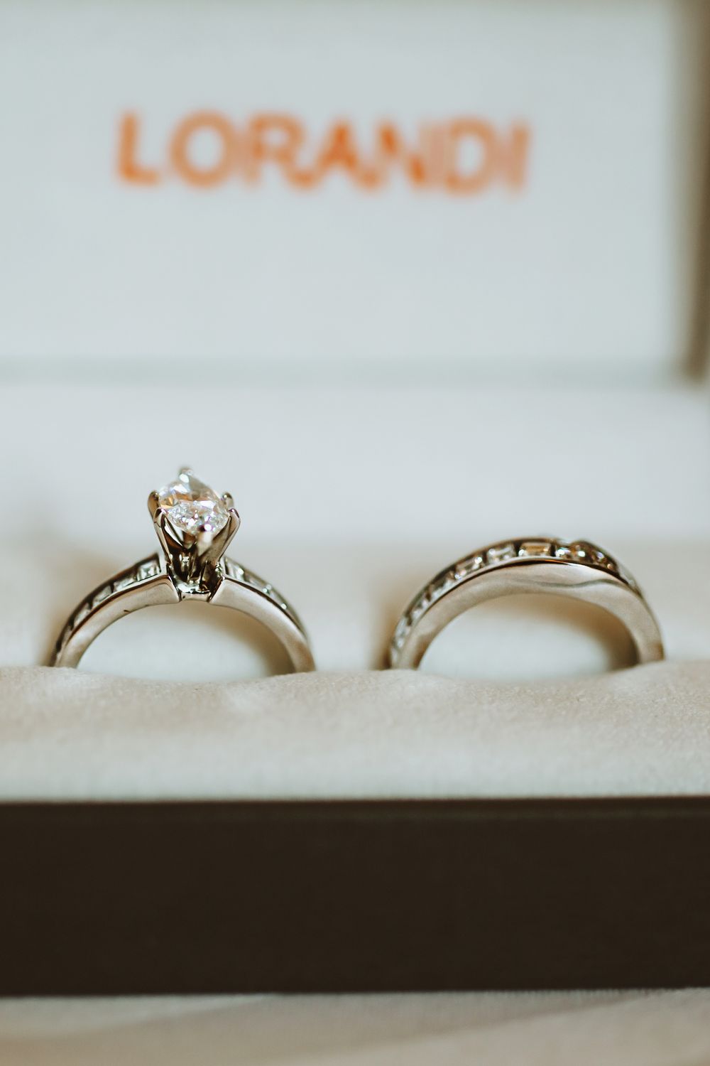 Diamond engagement ring and matching wedding band rest in white display box with Lorandi text visible above.