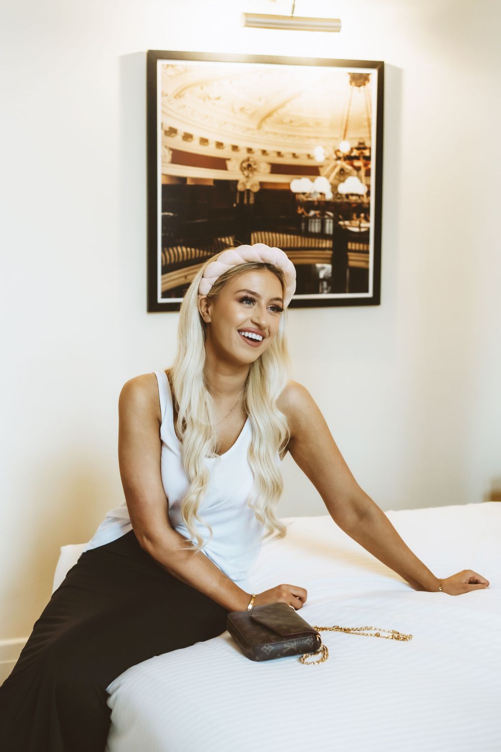 A series of photos showing a person in a white top lying on a dark bed with framed artwork on the wall.