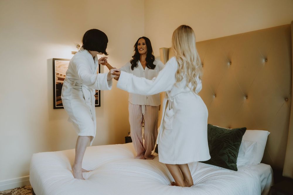 A sequence of four photos showing people in white clothing sitting and laughing together on a white bed.