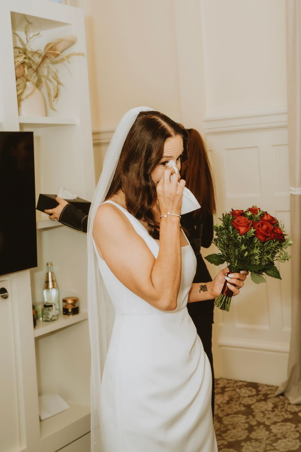 A sequence showing a person in white moving away while holding red roses in what appears to be a hallway.