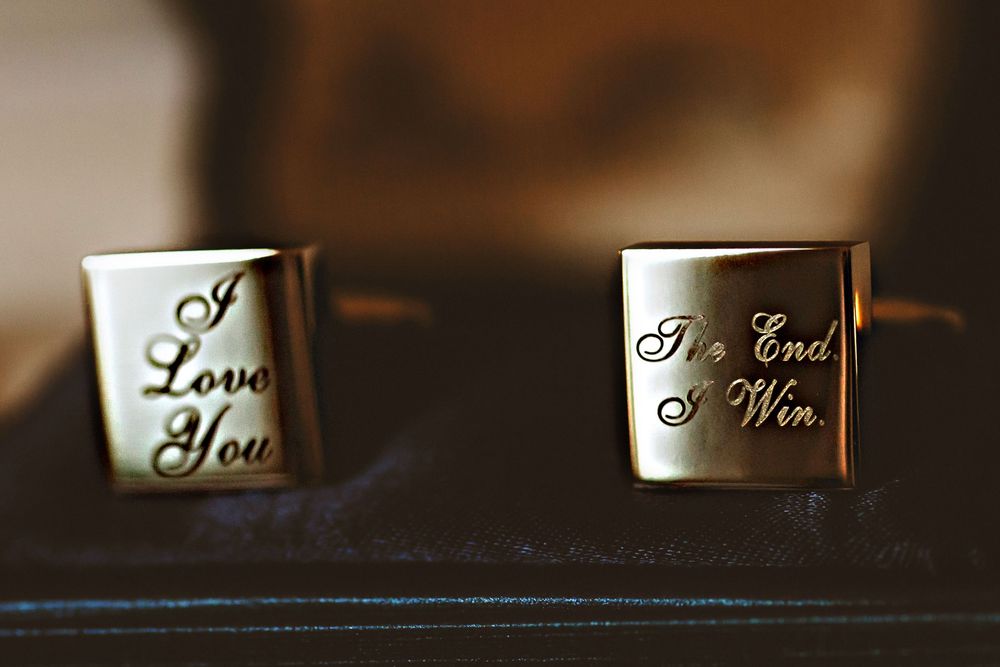 Decorative rings lined up showing engraved text details on their surfaces in dark moody lighting.