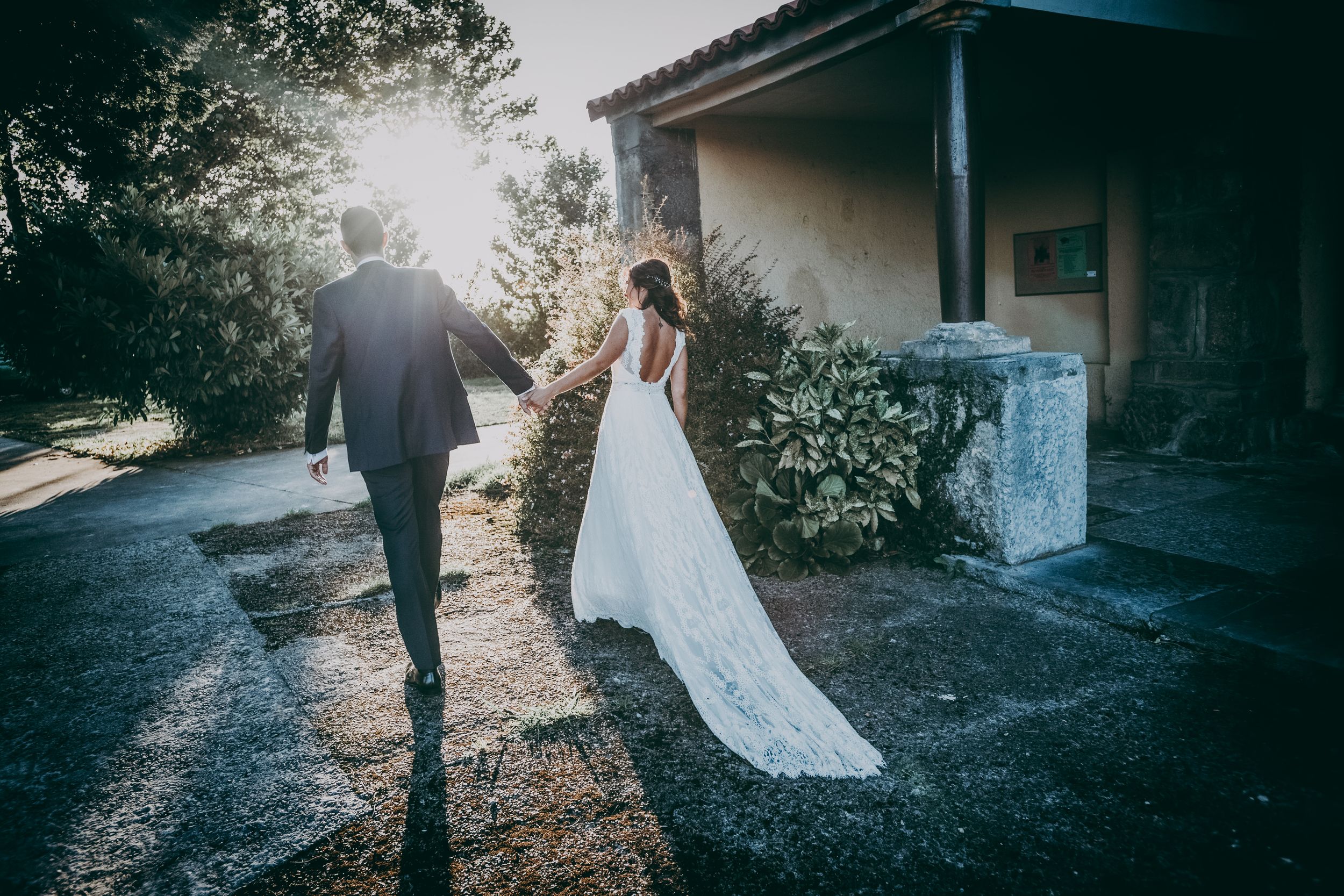 Pareja de novios caminando de la mano al atardecer tras la boda en Asturias — Fotografía documental por Juan Llavio