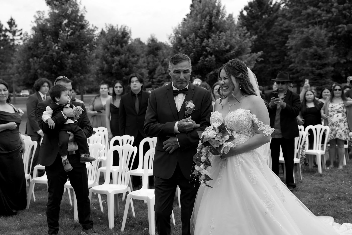Black and white photo series of an outdoor wedding ceremony shows guests seated in white chairs on a lawn.