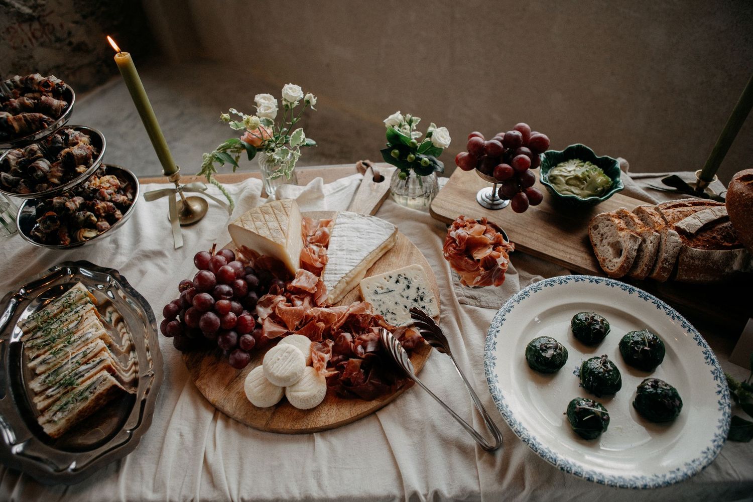 Elegant wedding charcuterie board with cheese, grapes, bread, and appetizers on a rustic table.