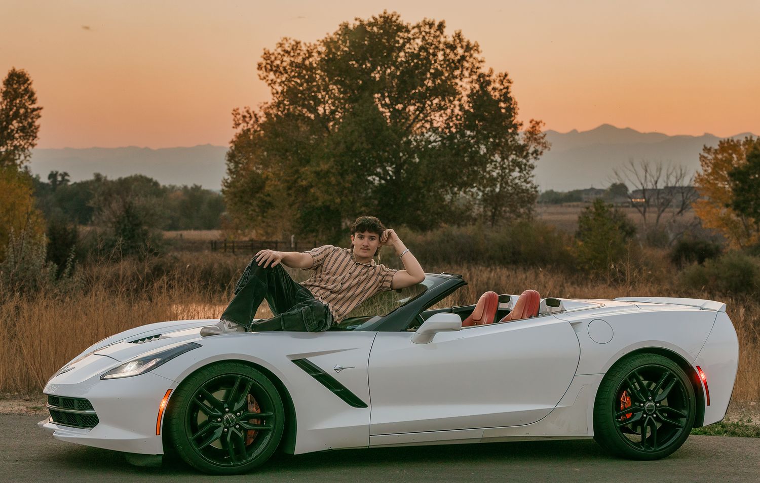 High School Senior posing on his Corvette at sunset for his Senior Portrait session.
