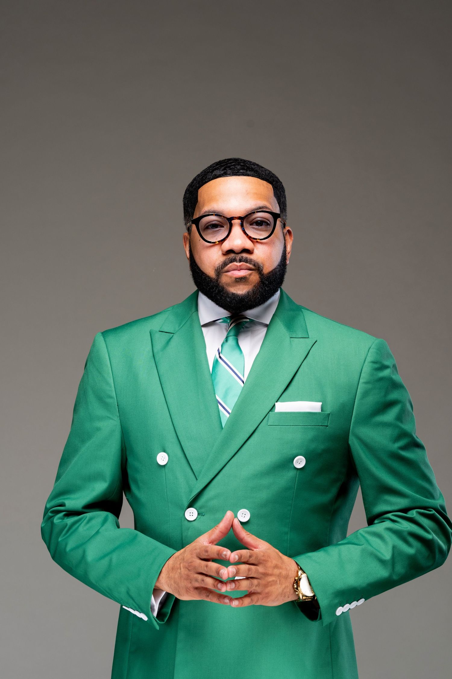 Professional headshot series showing person in beige suit and glasses with a neat beard against neutral background.