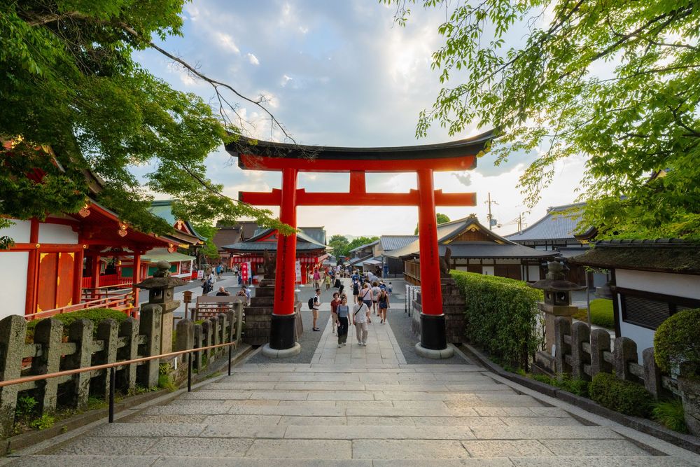 Traditional Japanese shrine pathway lined with red torii gates and stone steps leading uphill.