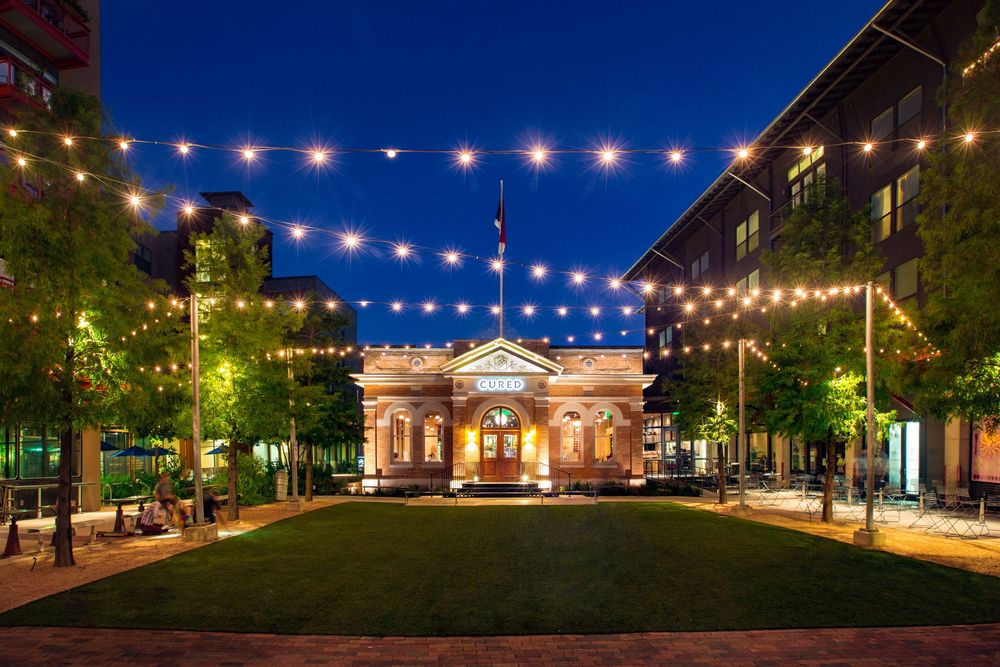 String lights illuminating outdoor courtyard at night with historic buildings.