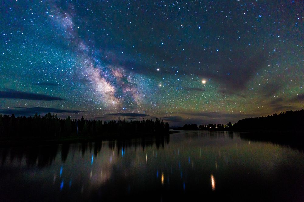 Stunning panorama of the Milky Way galaxy reflecting over a calm lake at night.
