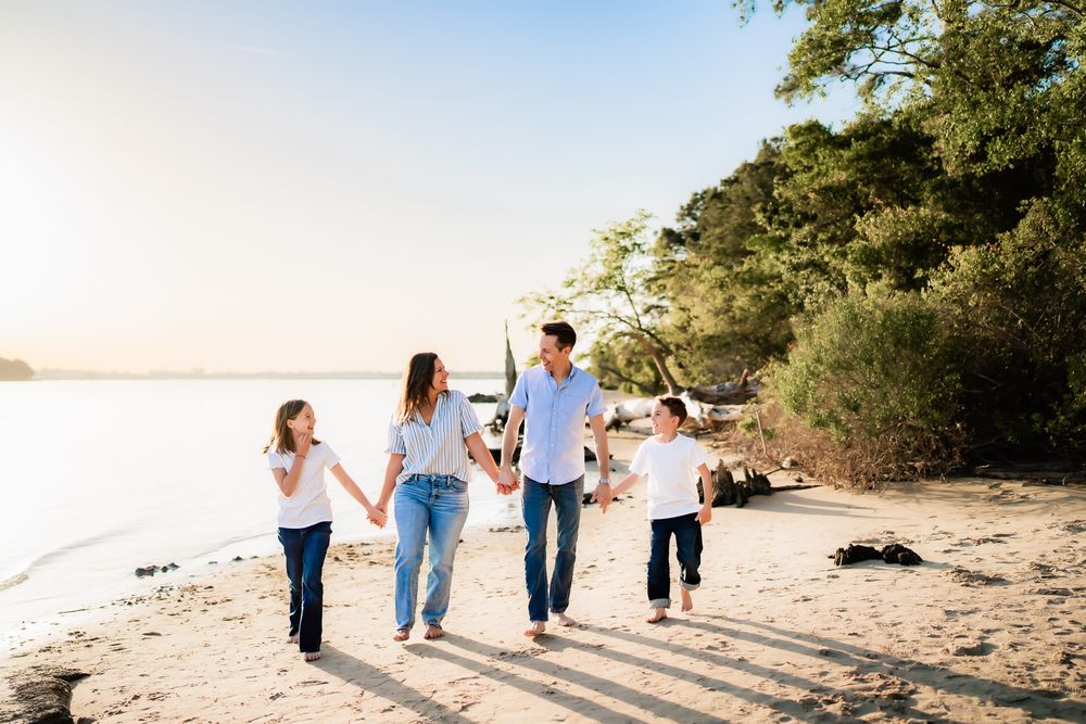 Family walking together and holding hands along a scenic beach path during golden hour sunset.