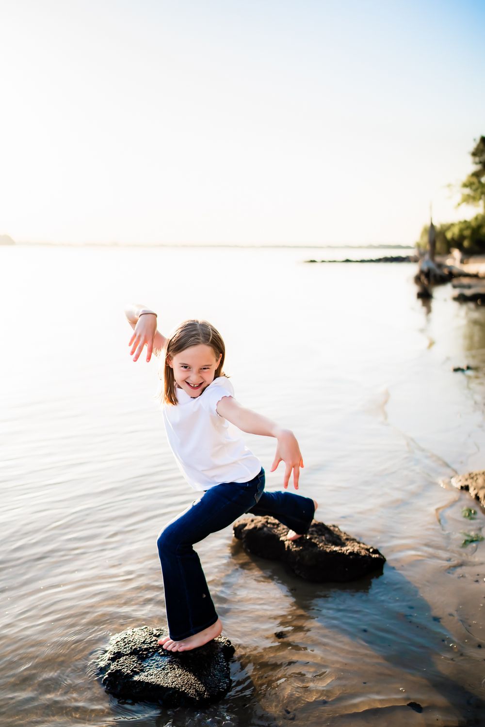 A playful scene at the beach shows energetic movement around rocks and water during sunset.