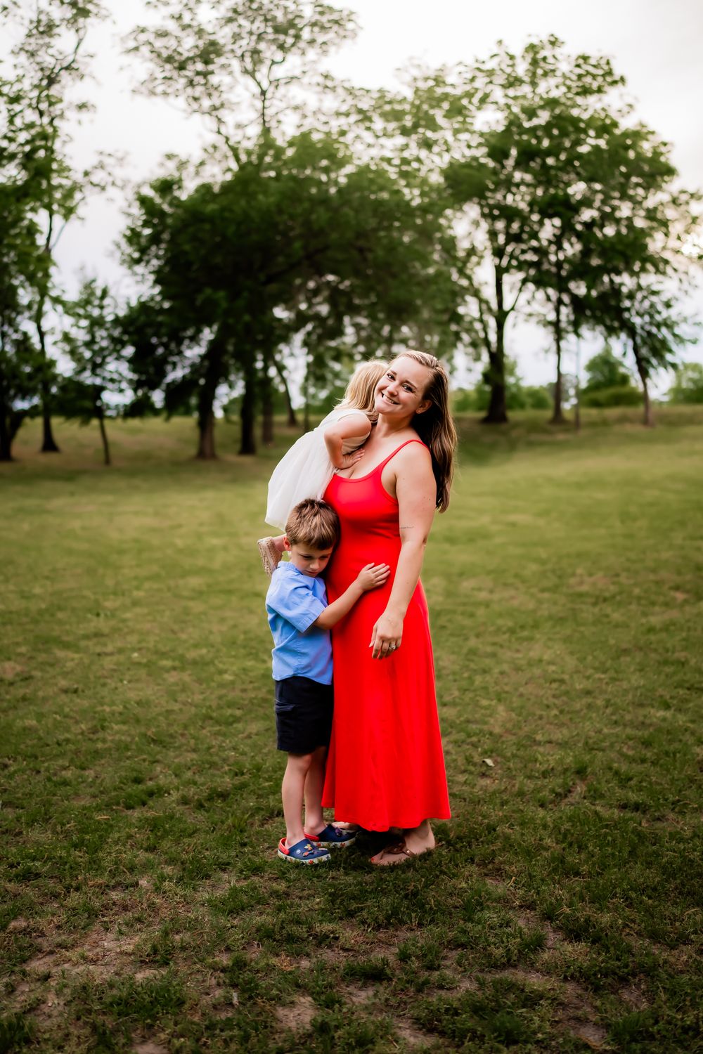 Touching sequence of a woman in a red dress sharing tender moments with a small child in a grassy field.