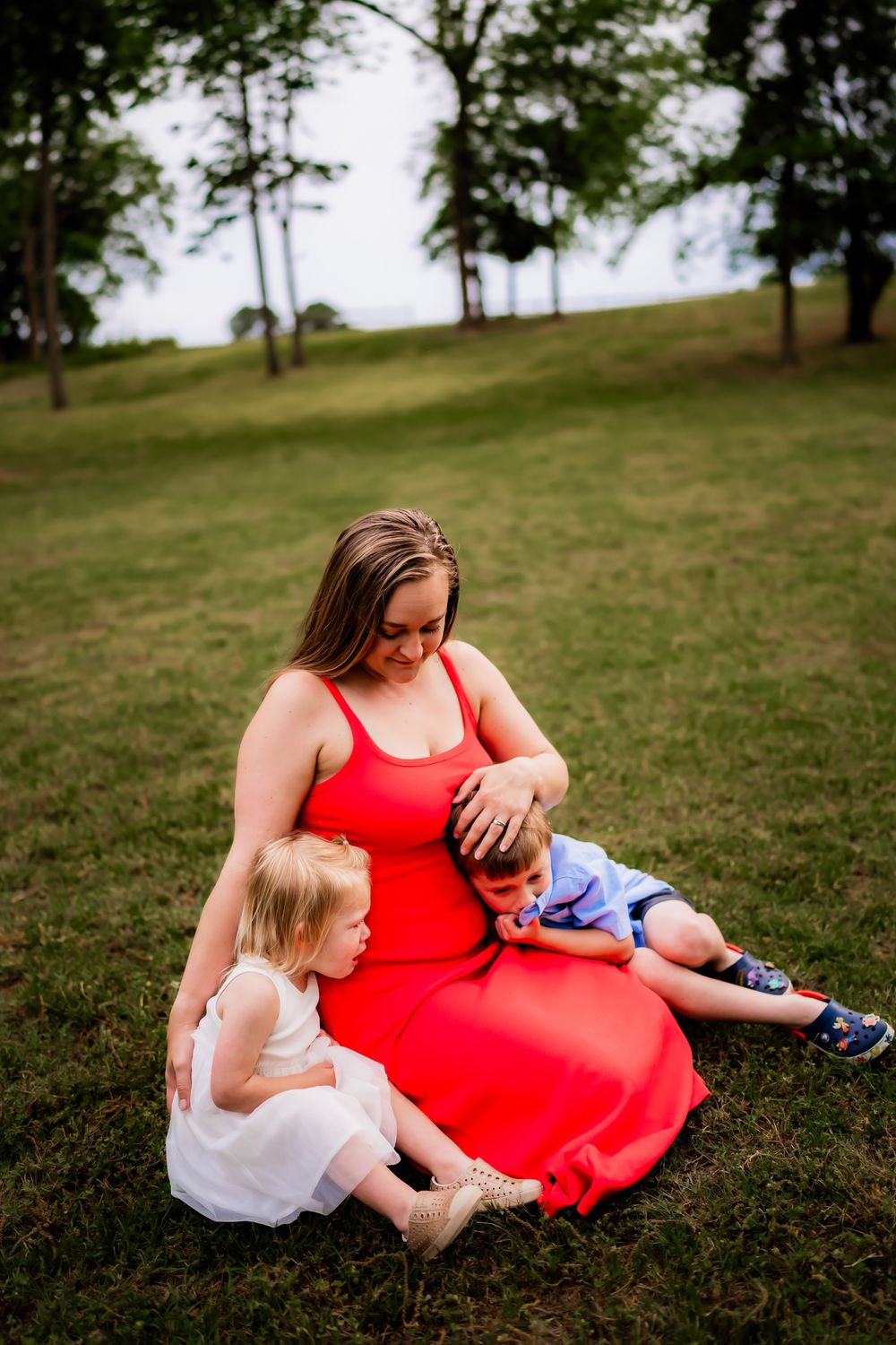 Family relaxing together on a grassy hill during a warm summer afternoon.