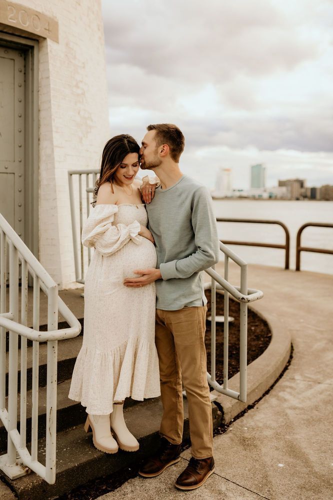 A couple shares an intimate moment on an urban rooftop terrace overlooking a cityscape at sunset.