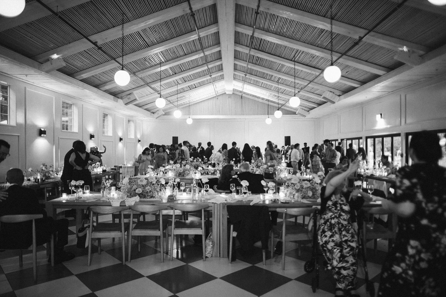 Long cafeteria dining hall filled with tables and overhead lighting for group seating and dining.
