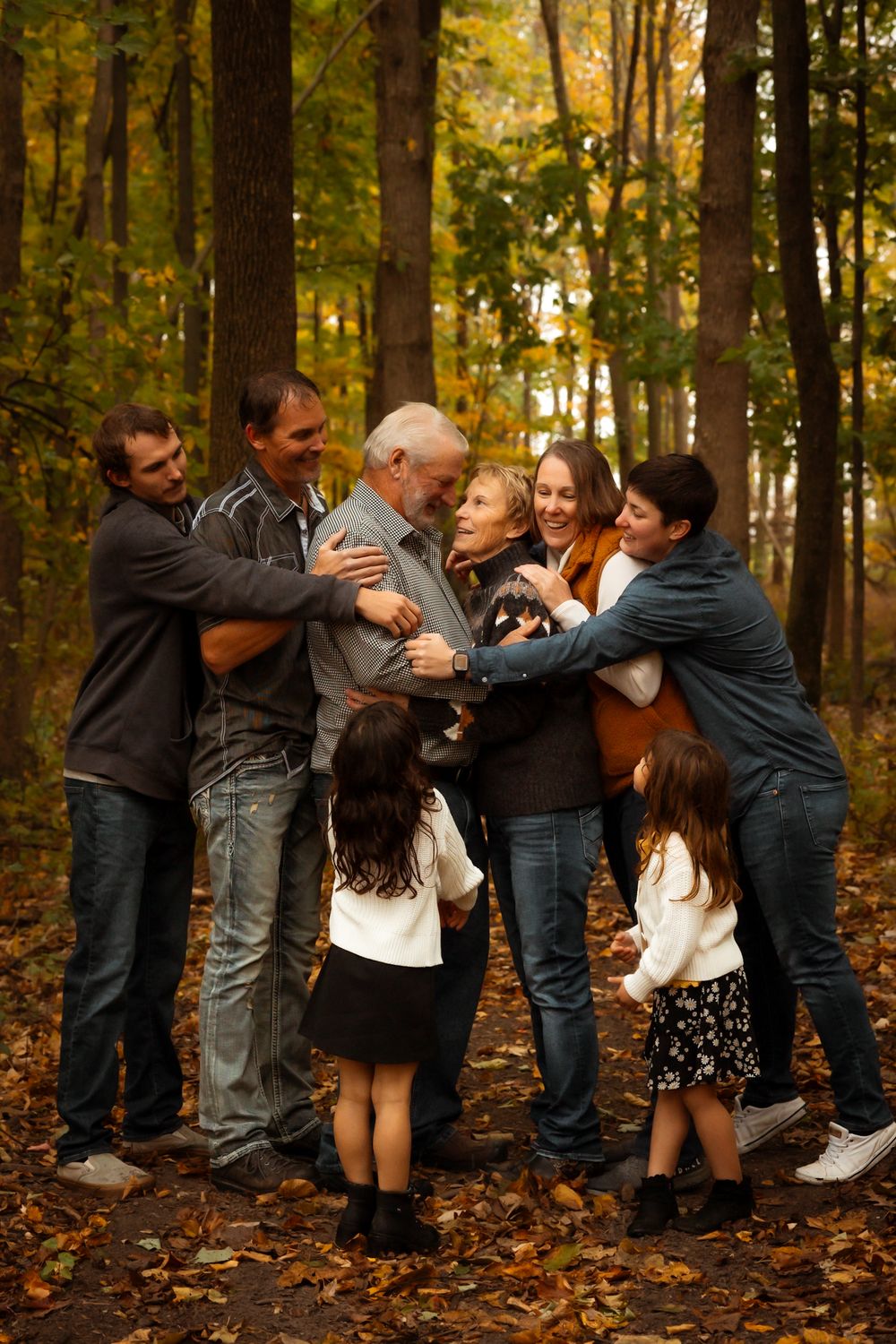 A sequence showing progressive frames of a playful group tussle amongst people in an autumn forest setting.