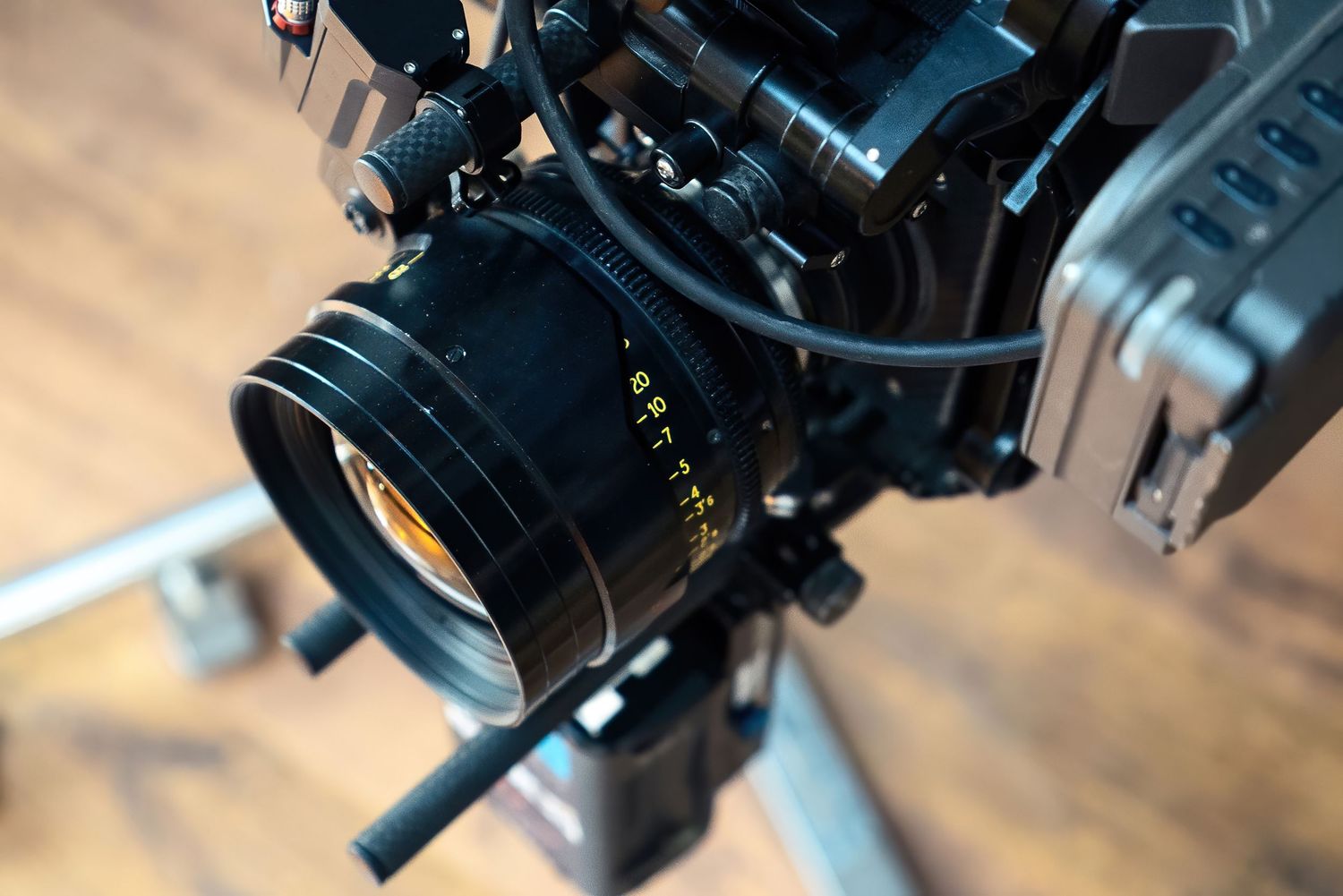 Professional video camera lens gear with focus adjustment controls mounted on a dark surface in low light conditions.