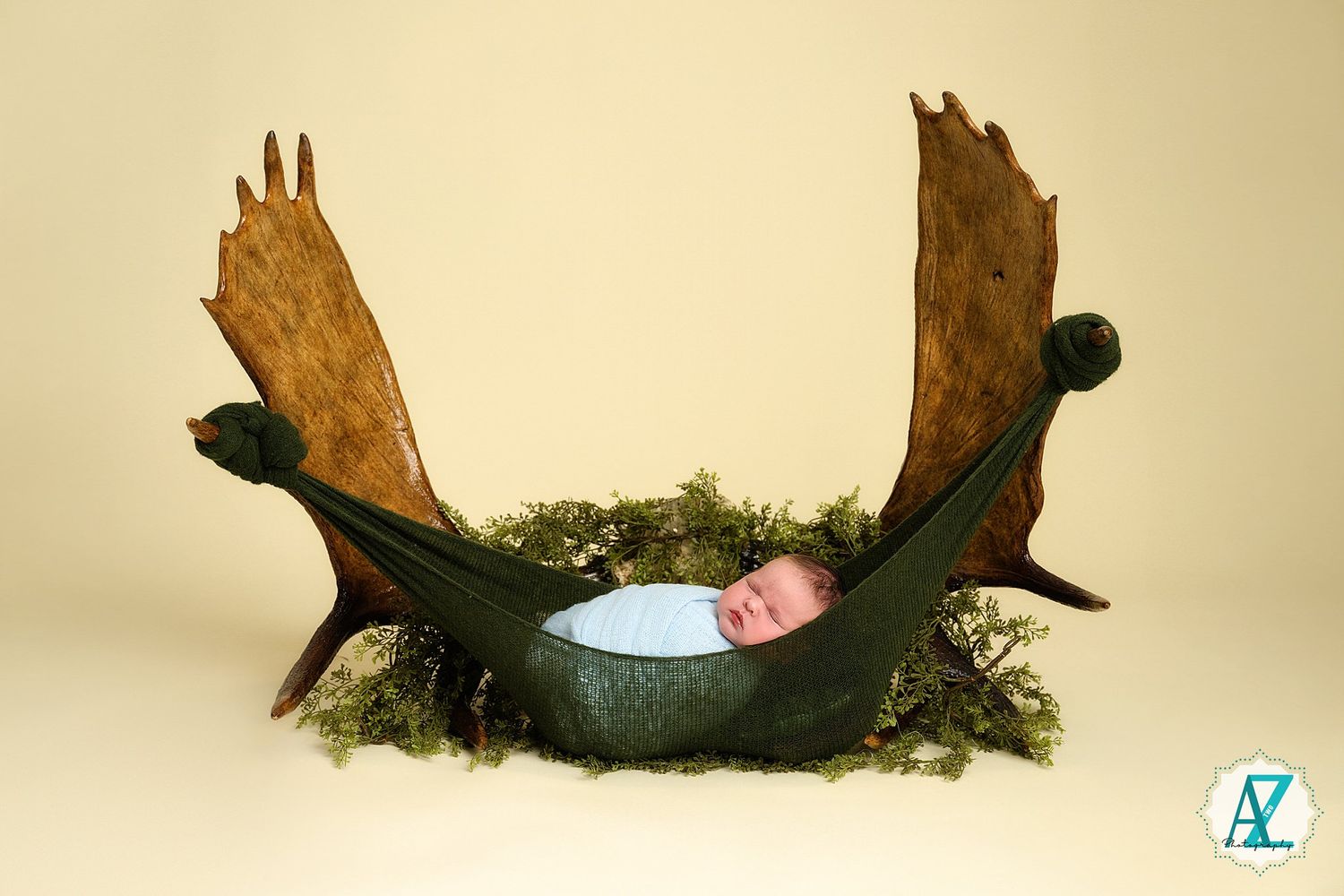 Multiple shots showing a wooden curved prop with moss and greenery being used in a newborn photography setup.