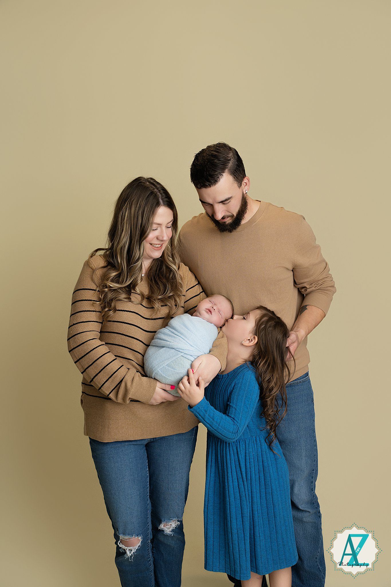 A family portrait series showing tender moments in matching tan and blue outfits against a neutral backdrop.