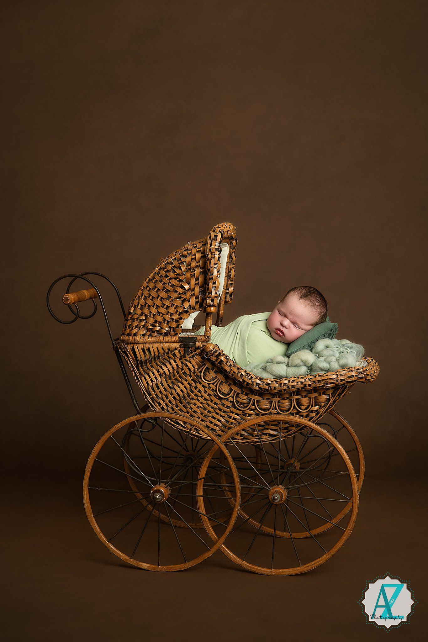 Antique woven wicker baby carriage with large wooden wheels photographed in warm brown tones.
