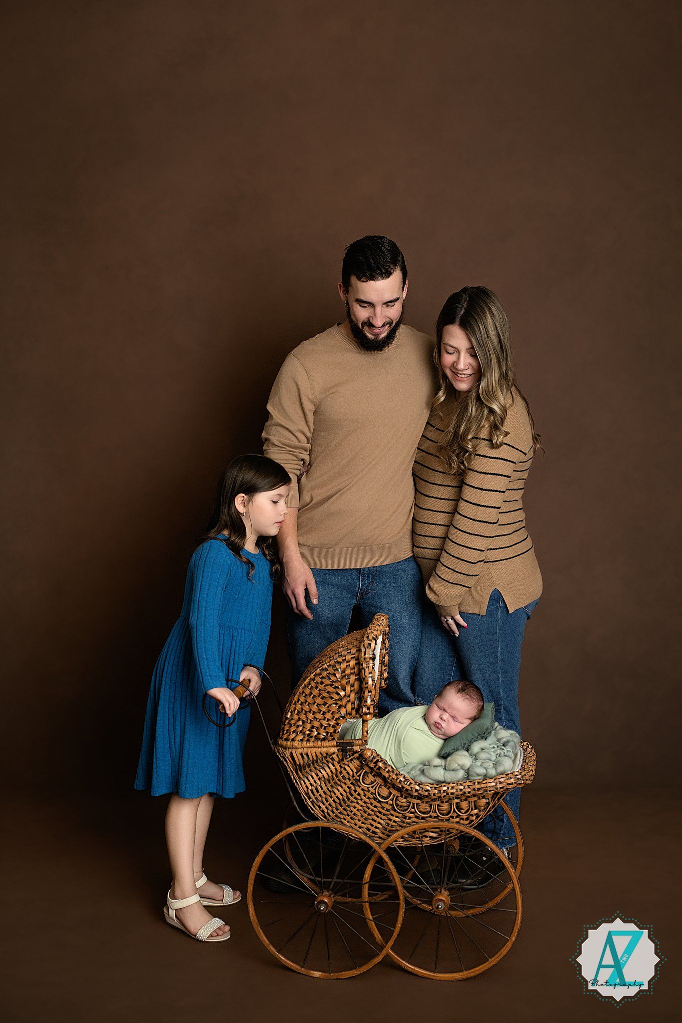 Professional family portrait series featuring an antique wicker baby carriage against a dark brown backdrop.
