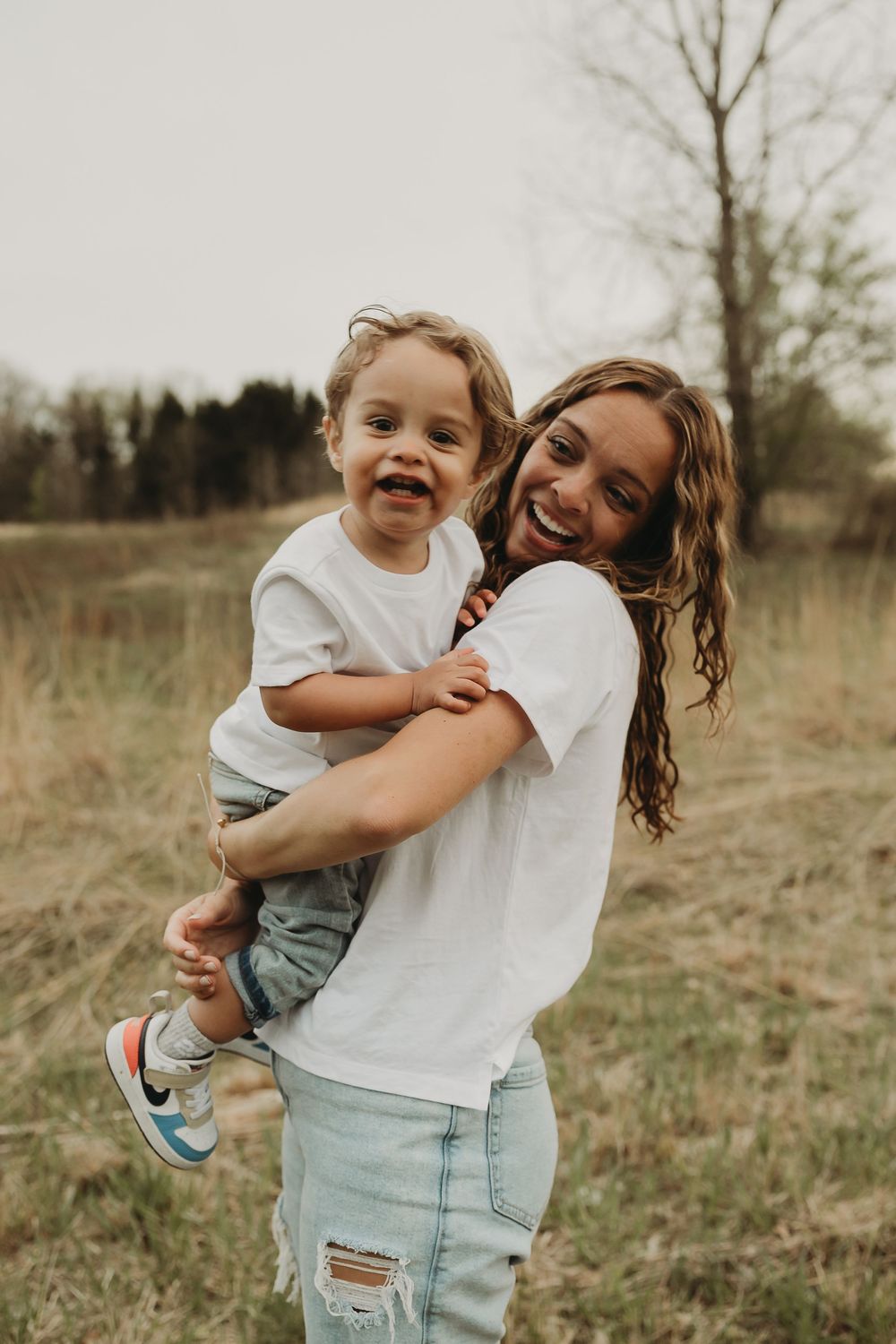 Heartwarming series of four candid moments showing playful hugs and laughter in a rustic outdoor field setting.