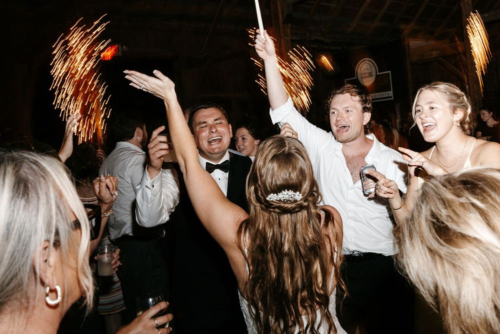 Young people dancing and celebrating at a lively nighttime party with sparklers casting festive light effects.