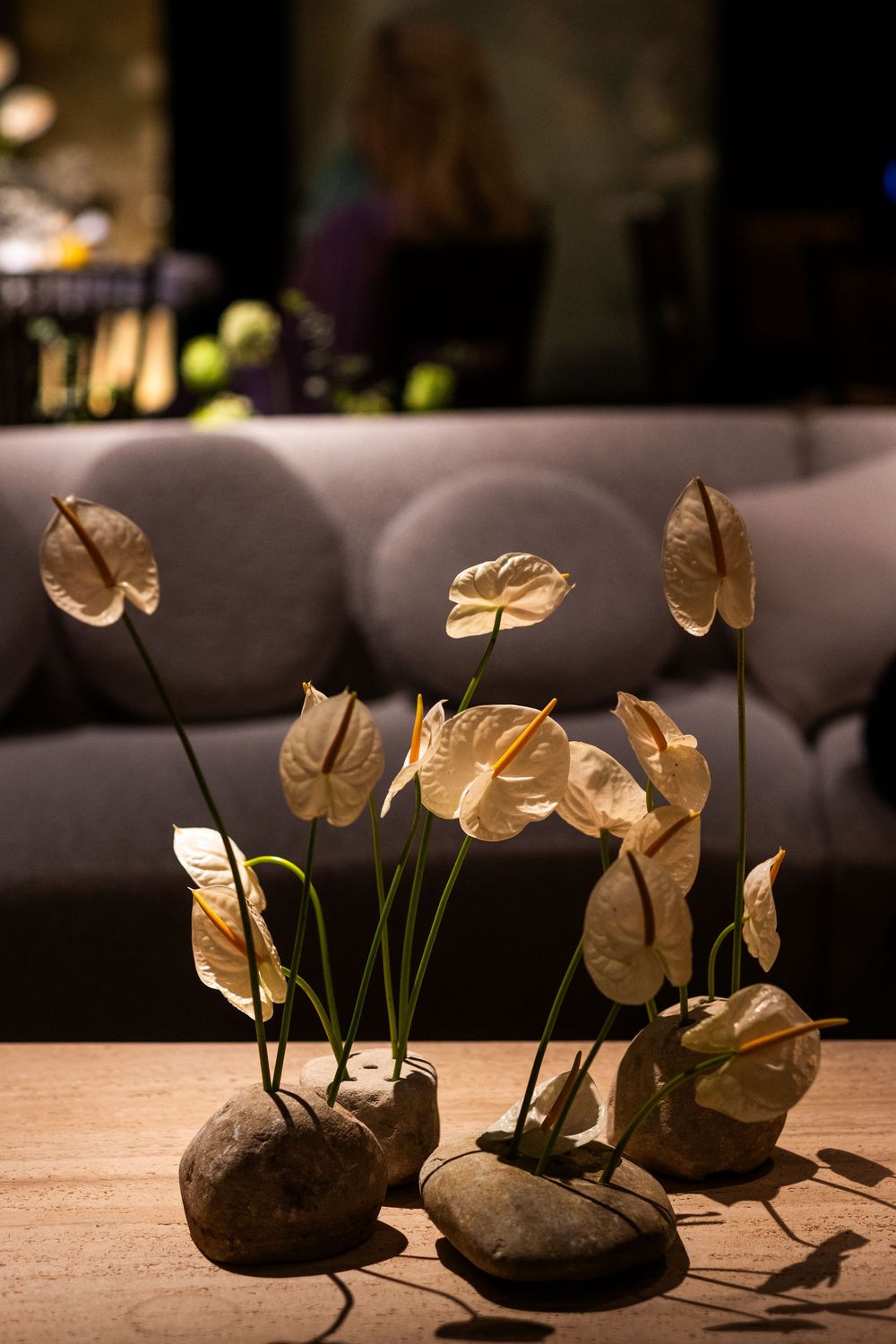 A series of decorative rocks with elegant golden butterflies and green stems arranged in a dark minimalist setting.