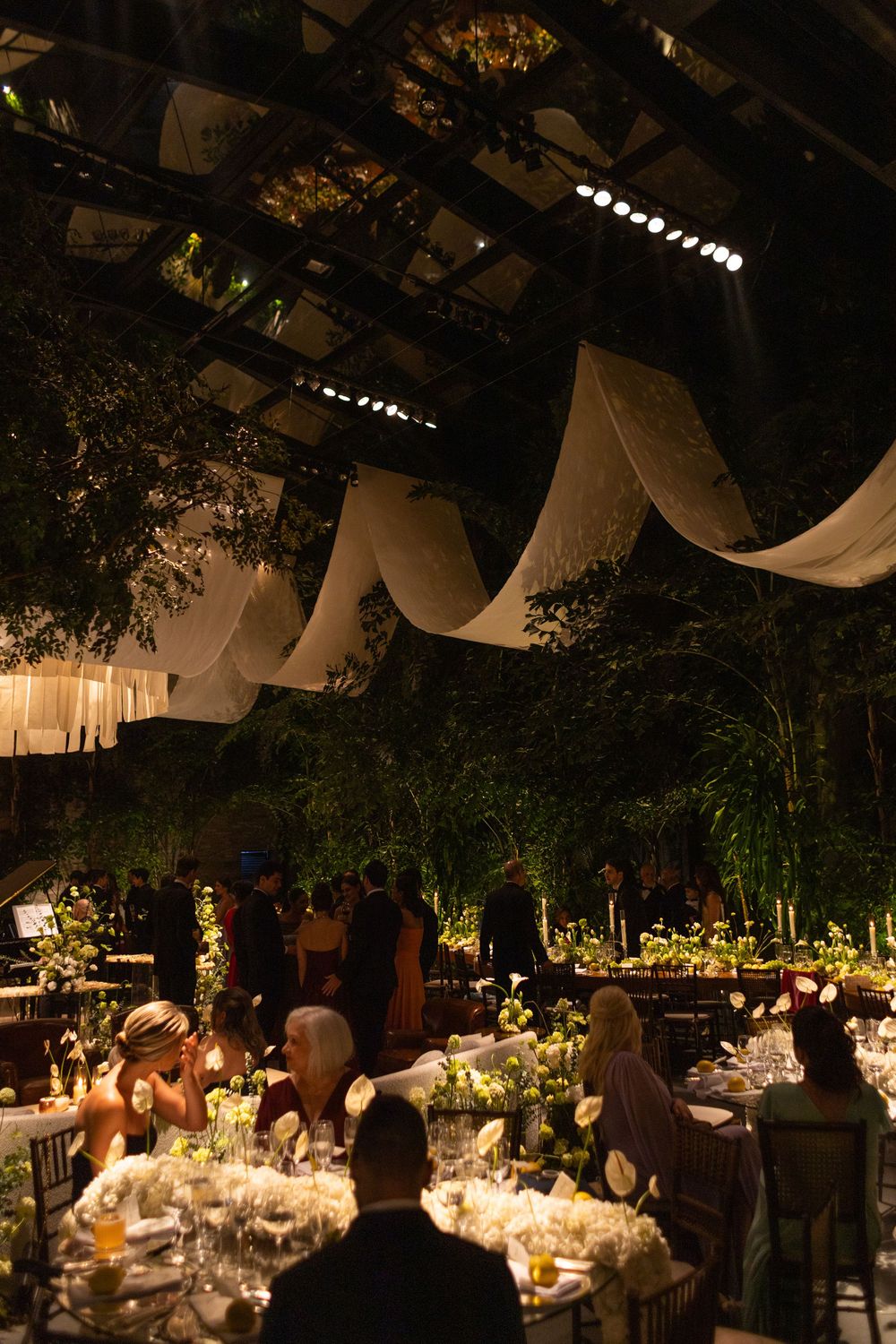 Elegant evening wedding reception with hanging drapery and glowing candlelit tables creating a romantic atmosphere.