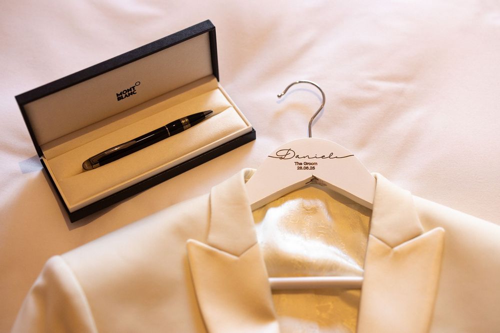 Six elegant beige dress hangers with gold hooks displayed in a row against a white background.