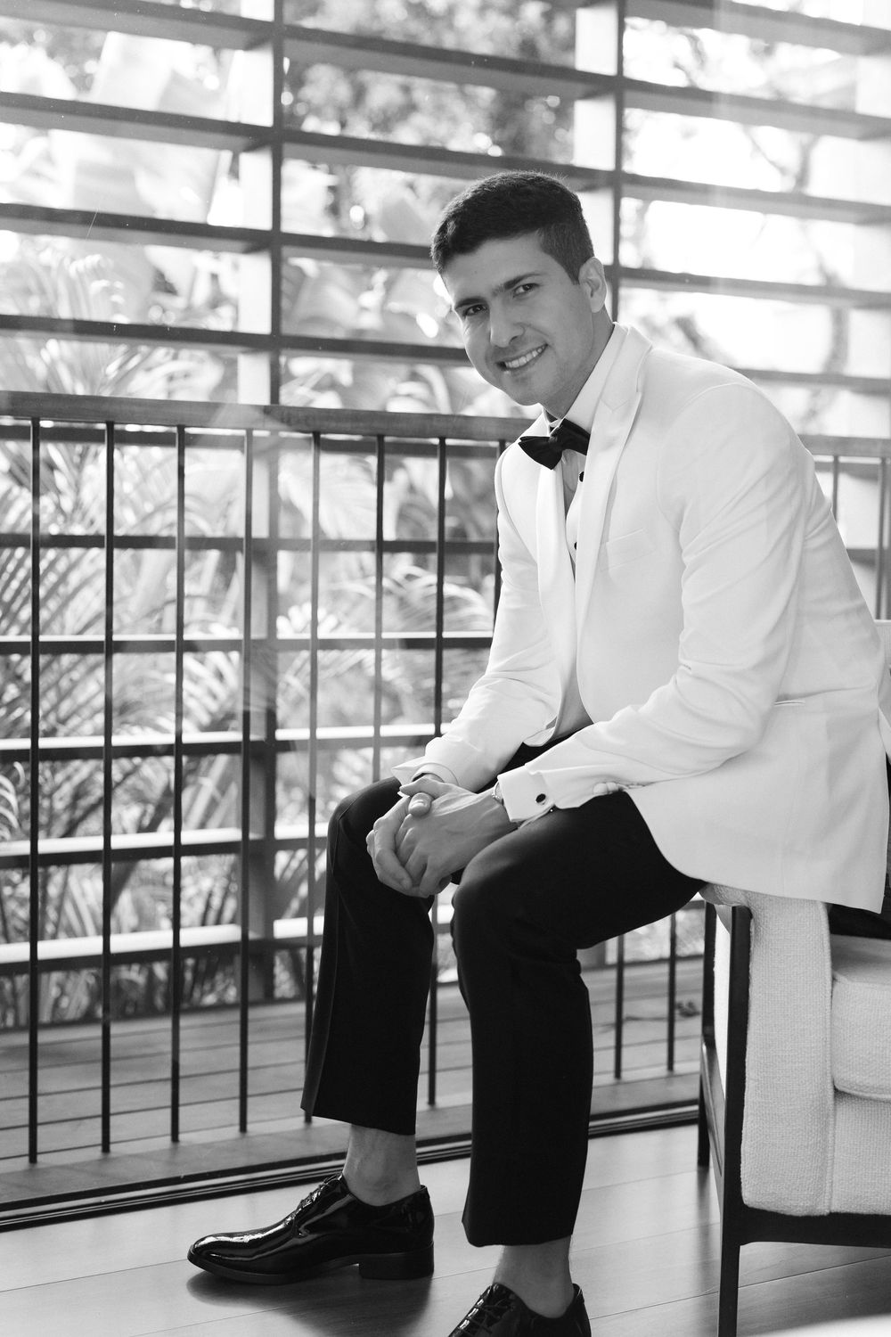 Black and white panoramic photo sequence showing five different poses of someone seated on a wooden floor against a railing.