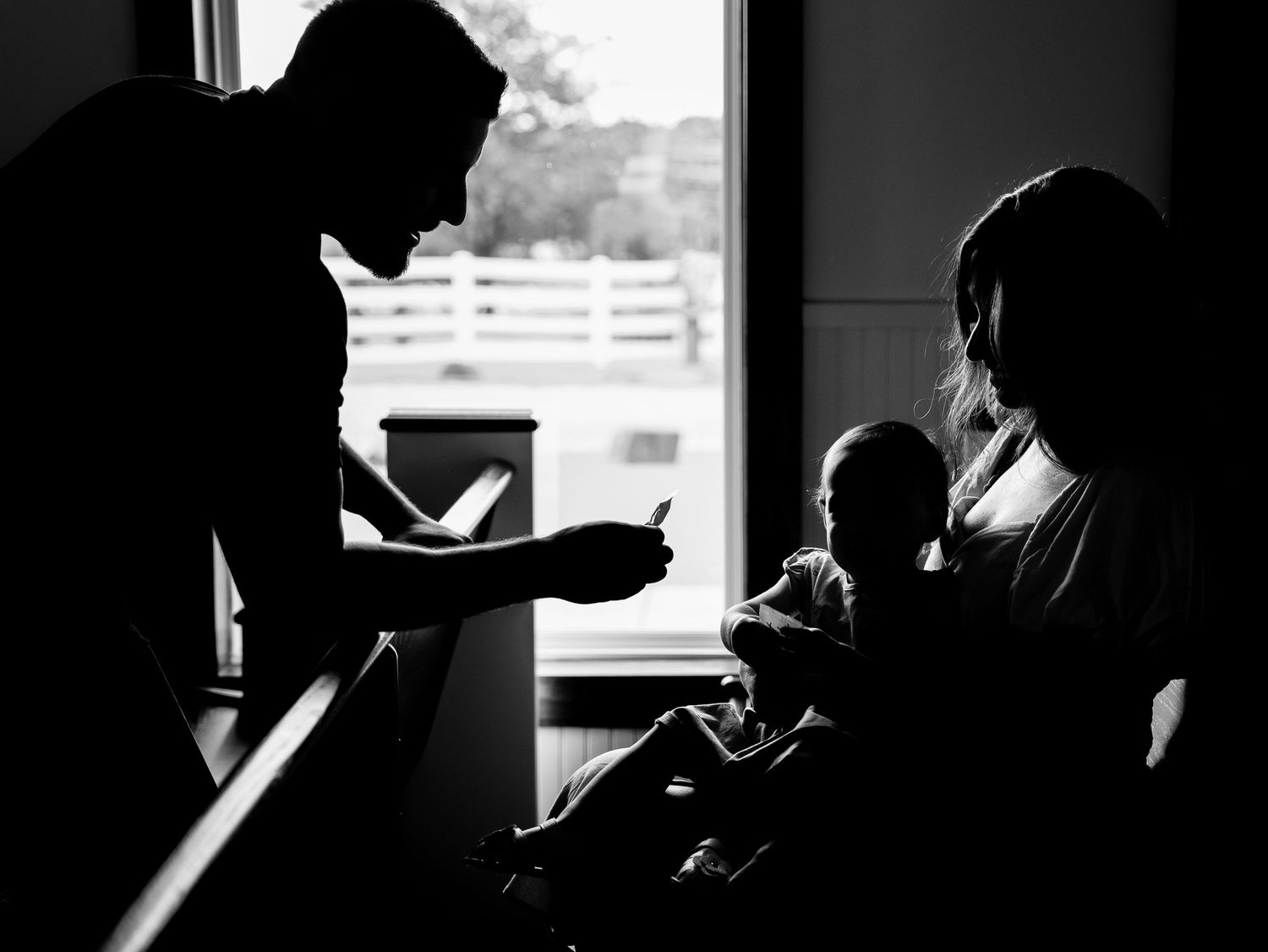 A person's silhouetted figure is visible in dark profile while reading near a backlit window.
