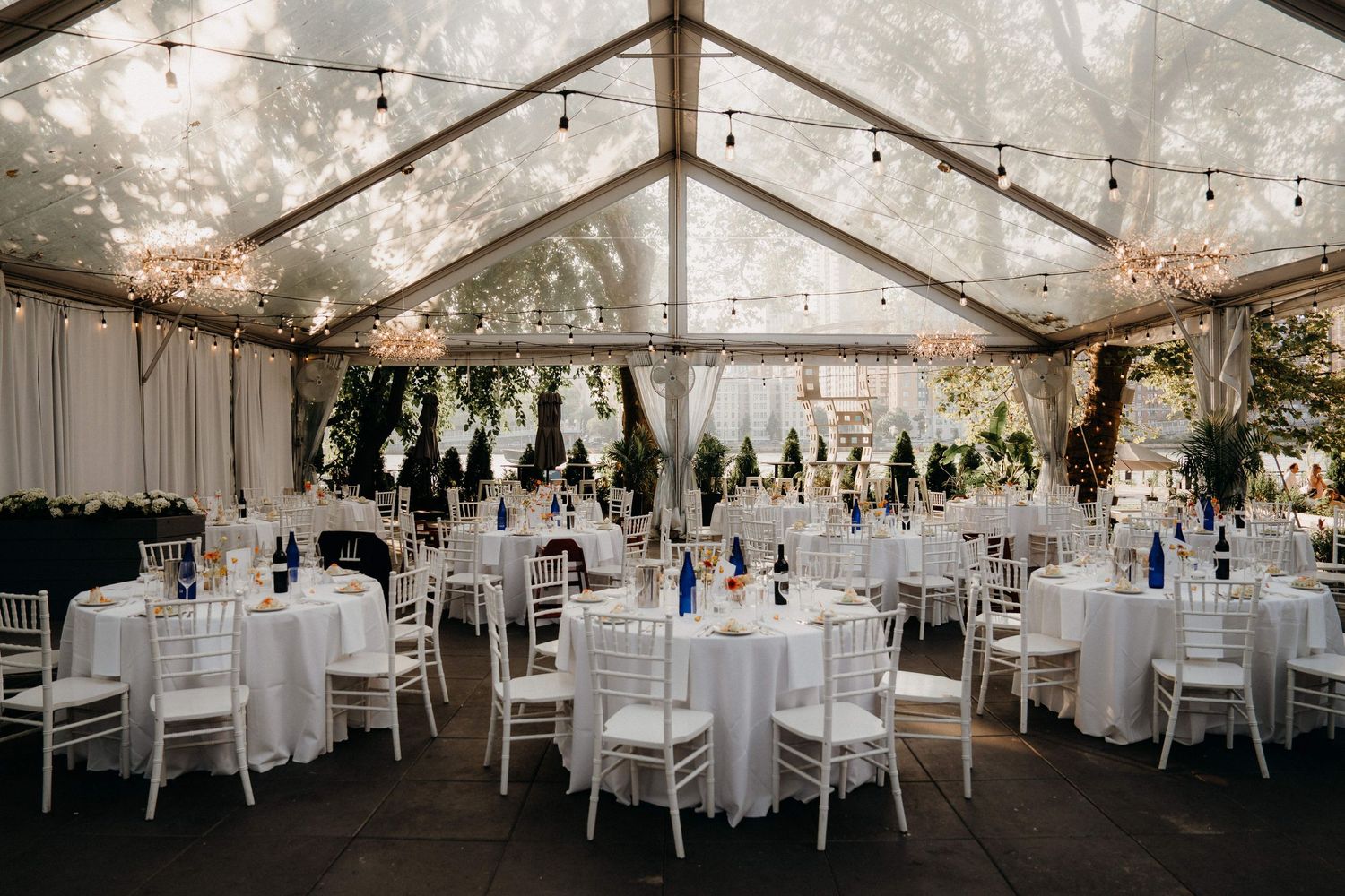 Elegant white wedding reception tent with crystal chandeliers at the Sanctuary Roosevelt Island NYC